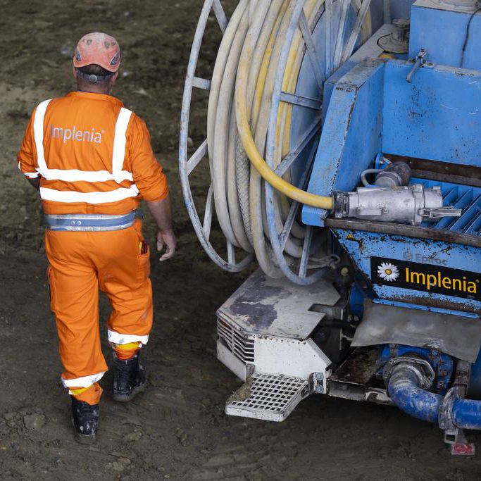 Travailleur d’Implenia sur le chantier du tunnel de Ligerz, avec une machine à béton projeté.