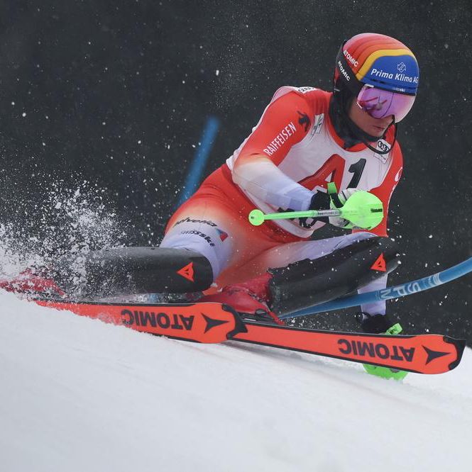 Skieur suisse en combinaison rouge lors de la première manche du slalom masculin à la Coupe du monde de ski alpin FIS à Kitzbühel, Autriche. Tanguy Nef effectue une descente rapide sous la neige.