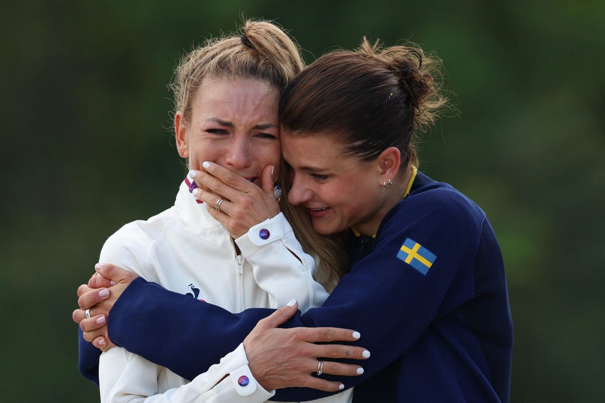 Silver-medallist Sweden's Jenny Rissveds (R) hugs France's Pauline Ferrand Prevot as she reacts while celebrating her gold medal victory on the podium after the women's cross-country mountain biking event during the Paris 2024 Olympic Games in Elancourt Hill venue in Elancourt, on July 28, 2024. (Photo by Emmanuel DUNAND / AFP)
