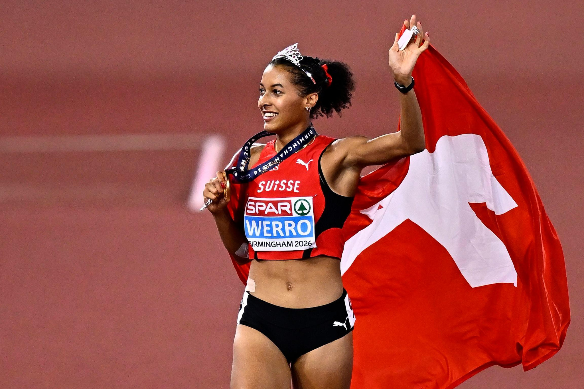 Athletin Werro feiert mit Schweizer Fahne und Medaille an den Leichtathletik-Europameisterschaften 2024 in Birmingham.