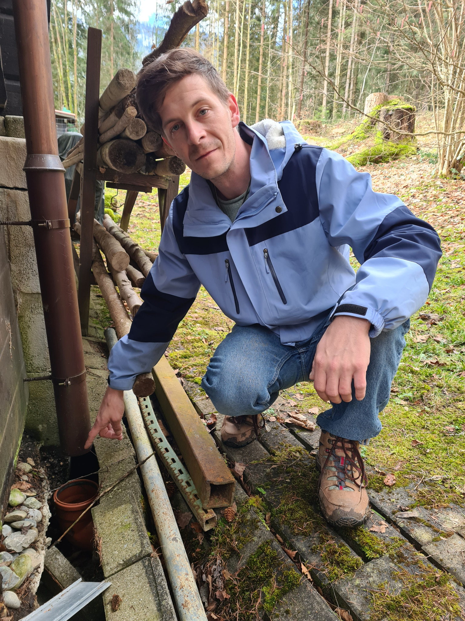 Gemeindepräsident Manuel Liechti zeigt auf einen Riss hinter einem Ferienhäuschen oberhalb des Weiermoos in der Gemeinde Wattenwil. Das Rohr passt nicht mehr zusammen.