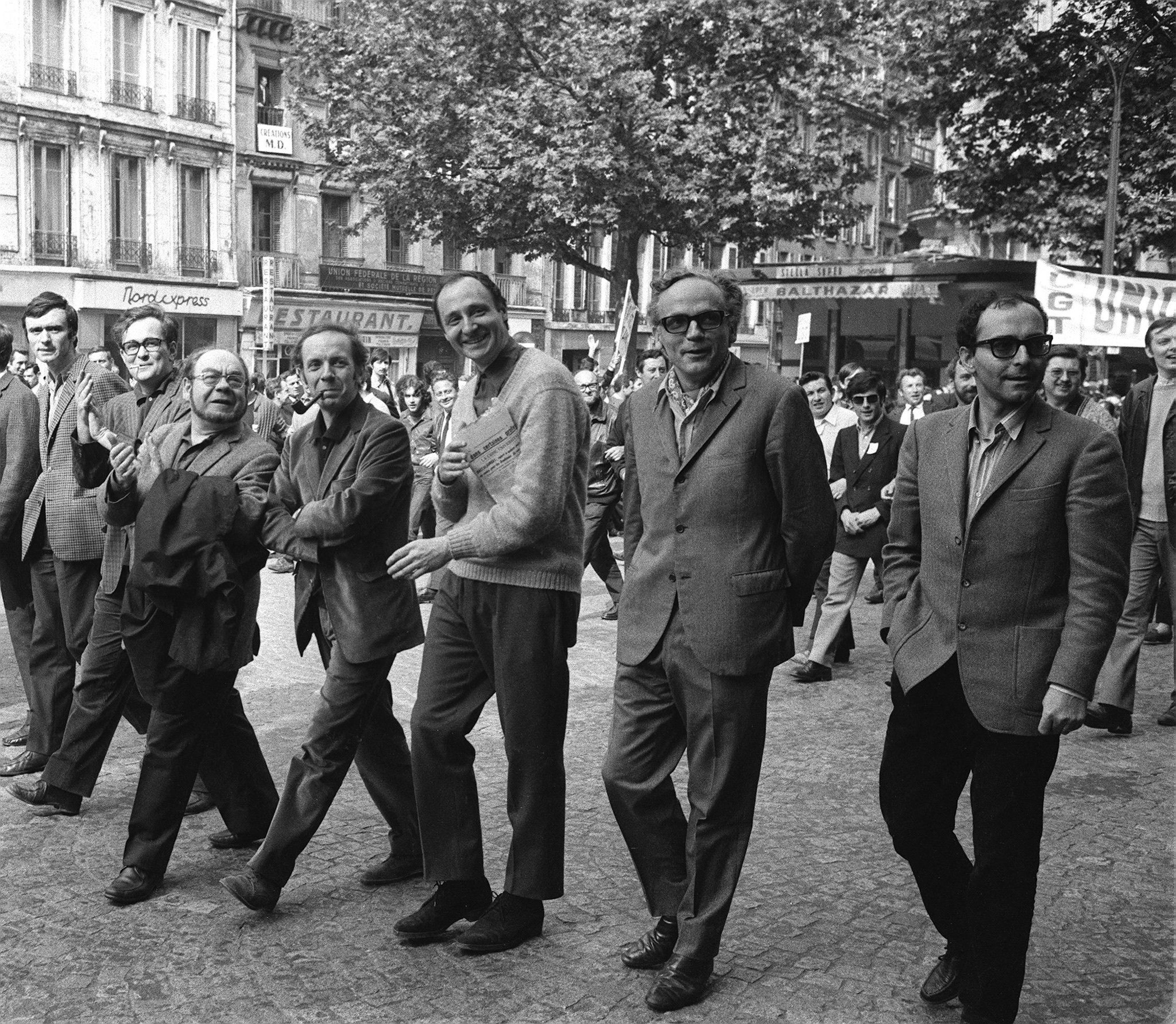 Jean-Luc Godard (à droite), le poète Alain Jouffroy (deuxième depuis la gauche) et le poète communiste Eugène Guillevic (troisième depuis la gauche) marchent à Paris, le 29 mai 1968, en compagnie des membres du Syndicat des acteurs pendant la grève générale de mai-juin 1968.