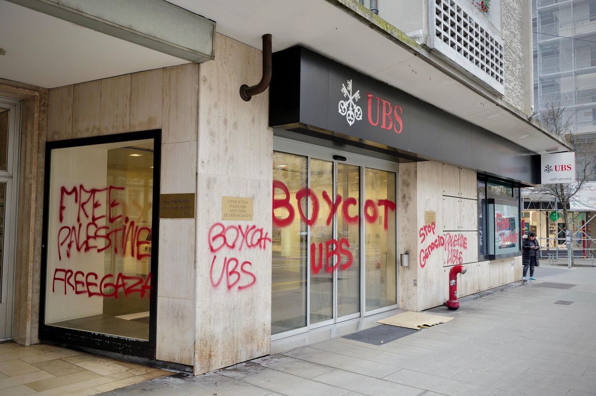 Façade d’une banque UBS avec des graffitis rouges disant ’Boycott UBS’ et ’Free Palestine Free Gaza’.