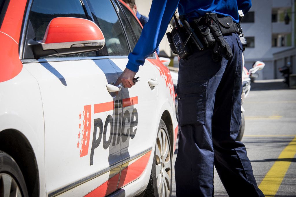 Un policier ouvre une voiture de la police cantonale valaisanne.