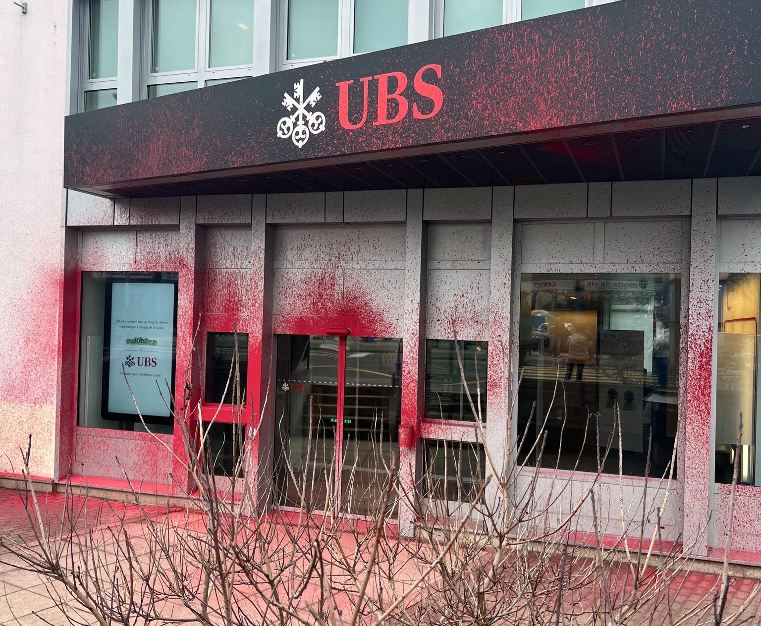 Façade de la banque UBS éclaboussée de peinture rouge, à Genève.