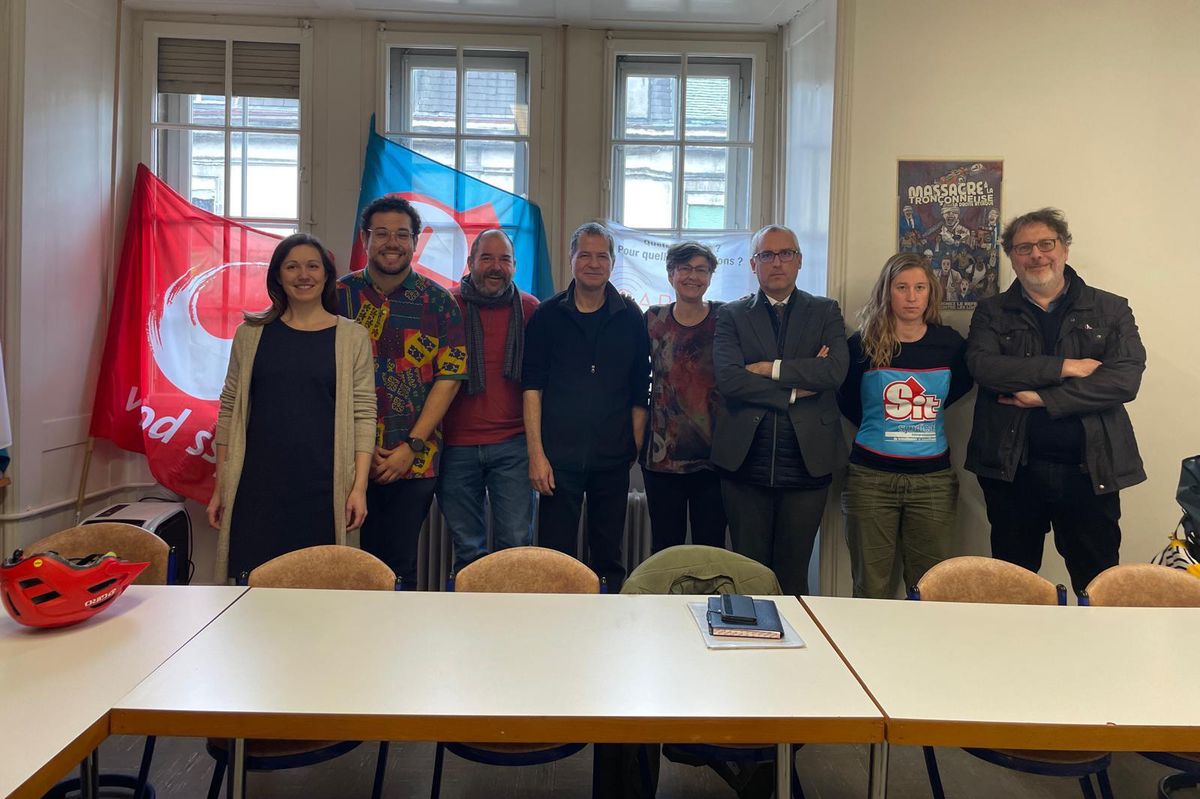 Groupe de personnes posant devant des drapeaux colorés dans une salle de réunion.