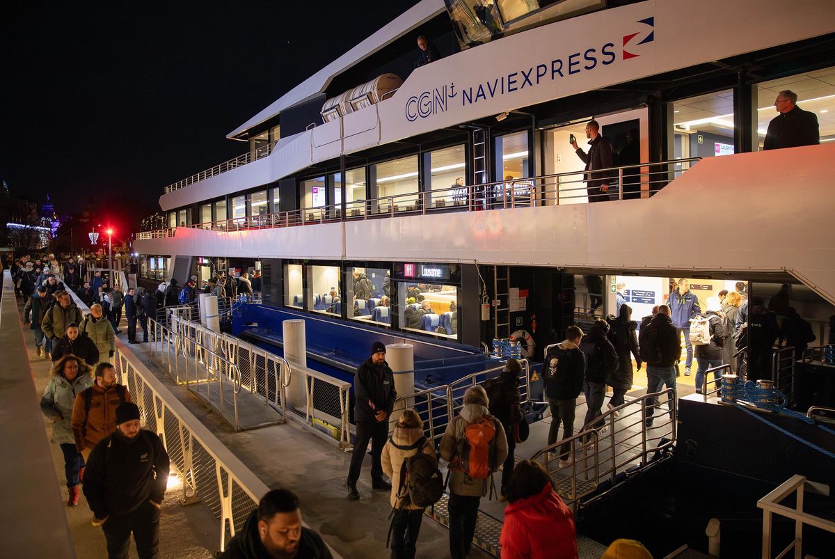 Passagers embarquant sur le Naviexpress de la CGN pour son premier voyage entre Évian et Lausanne, illuminé de nuit.