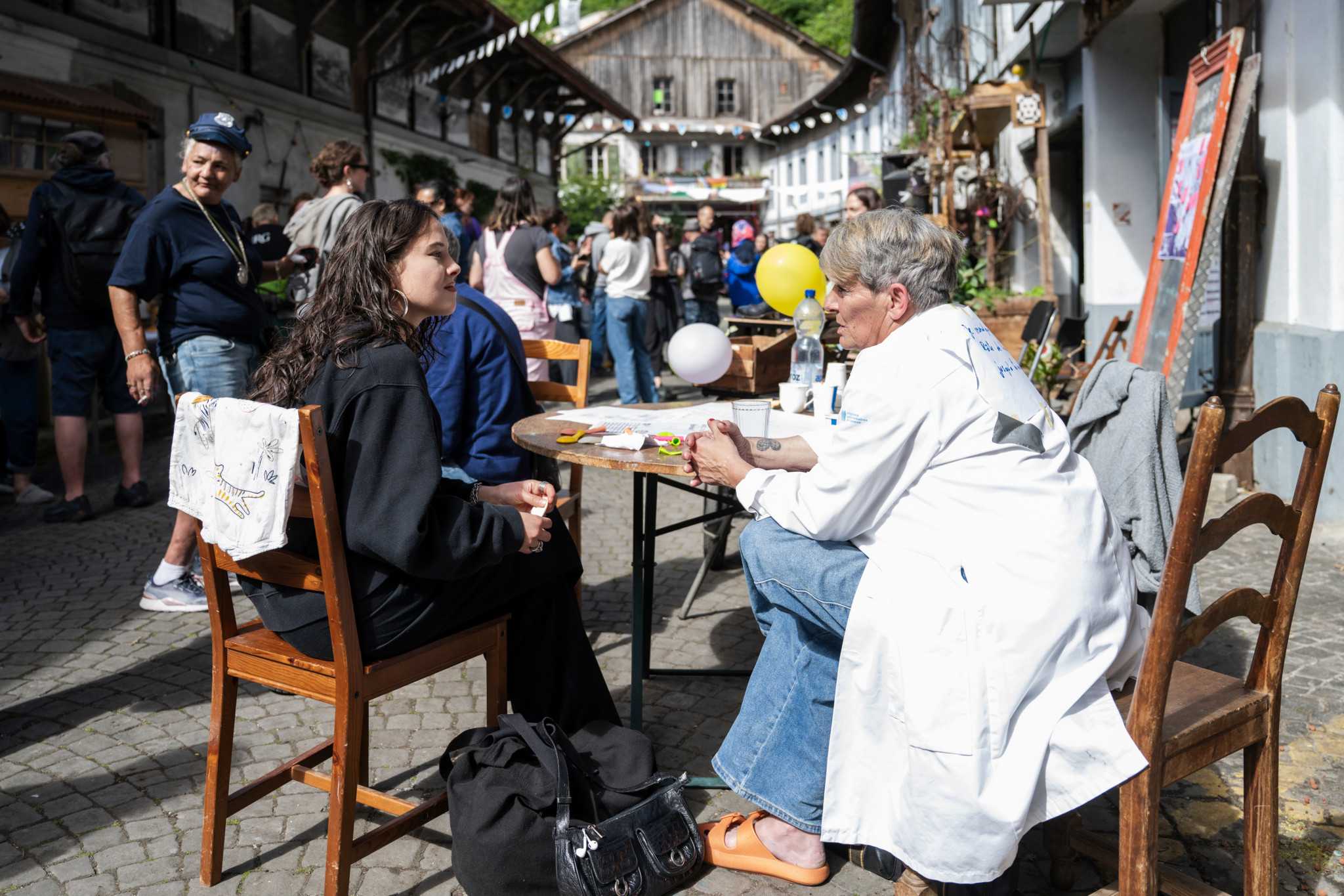 Rencontre internationale de femmes sans-abri à Lausanne: deux femmes échangent lors de l’événement public au Vallon, avec d’autres participants en arrière-plan.