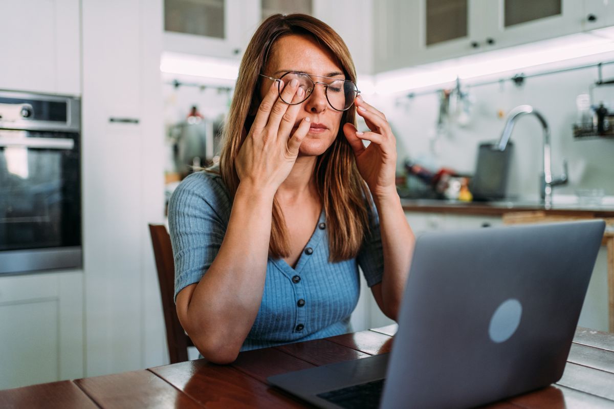 Stressed woman working from home. Frustrated businesswoman with head in hands sitting on the desk at home. Overworked young businesswoman sitting in front of laptop and holding head. Home office concept.
