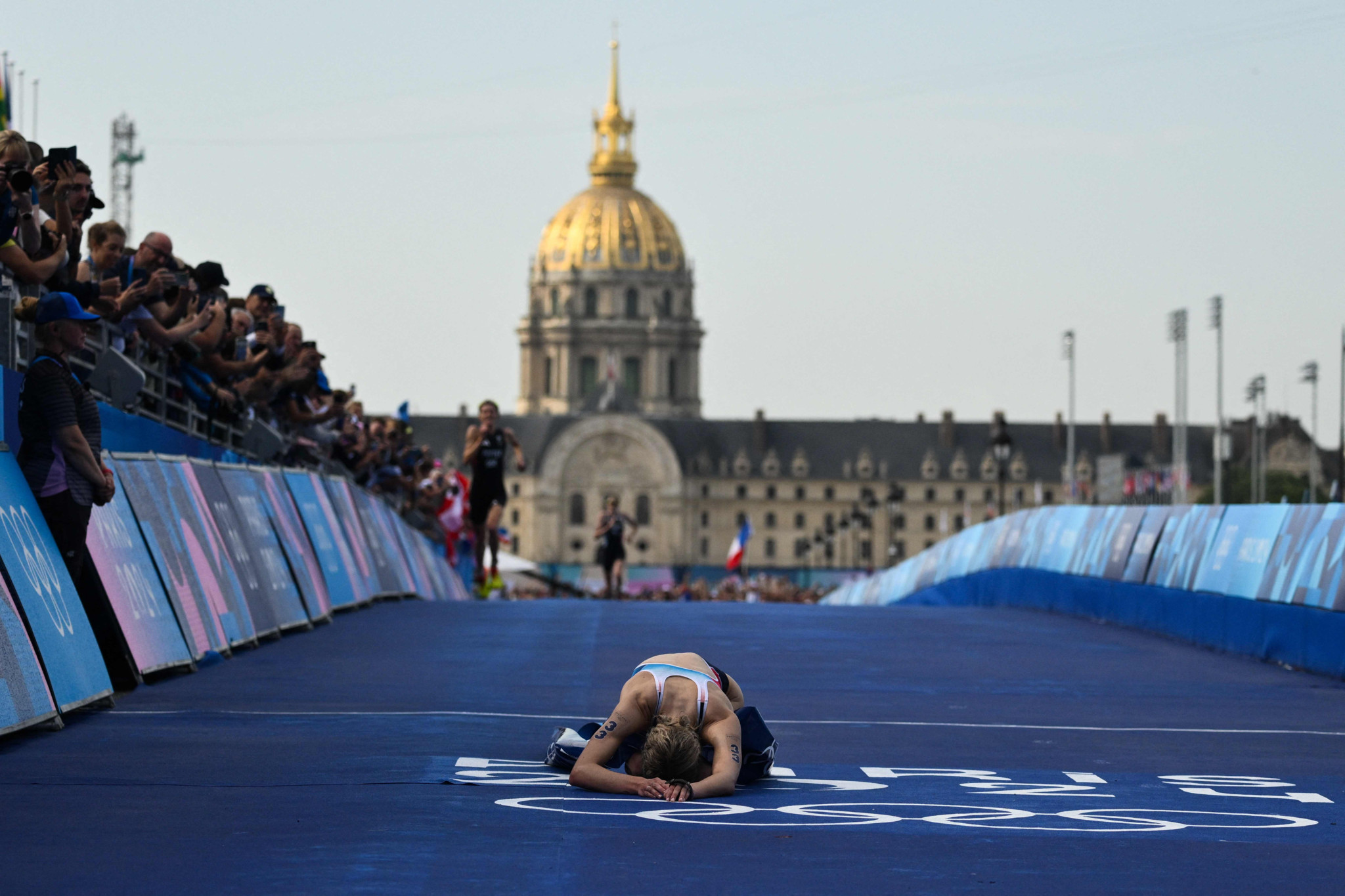 TOPSHOT - France's Cassandre Beaugrand reacts after crossing the finish on the Pont Alexandre III at the end of the   women's individual triathlon race at the Paris 2024 Olympic Games in central Paris on July 31, 2024. (Photo by Jeff PACHOUD / AFP)