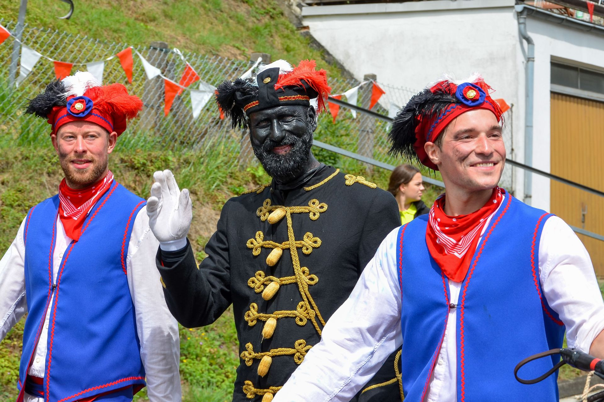 Drei Männer in historischen Kostümen beim Grenzgang 2019 in Biedenkopf, einer in schwarzer Uniform mit Goldverzierungen, zwei in blau-roter Tracht.