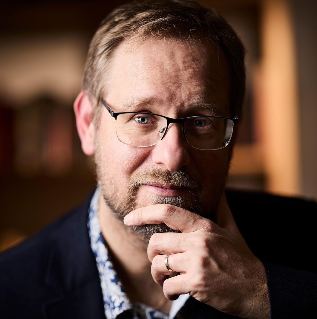 Portrait du Professeur Dominic Rohner, professeur d’économie à l’Institut de hautes études internationales et du développement de Genève, photographié pensivement avec la main sur le menton.