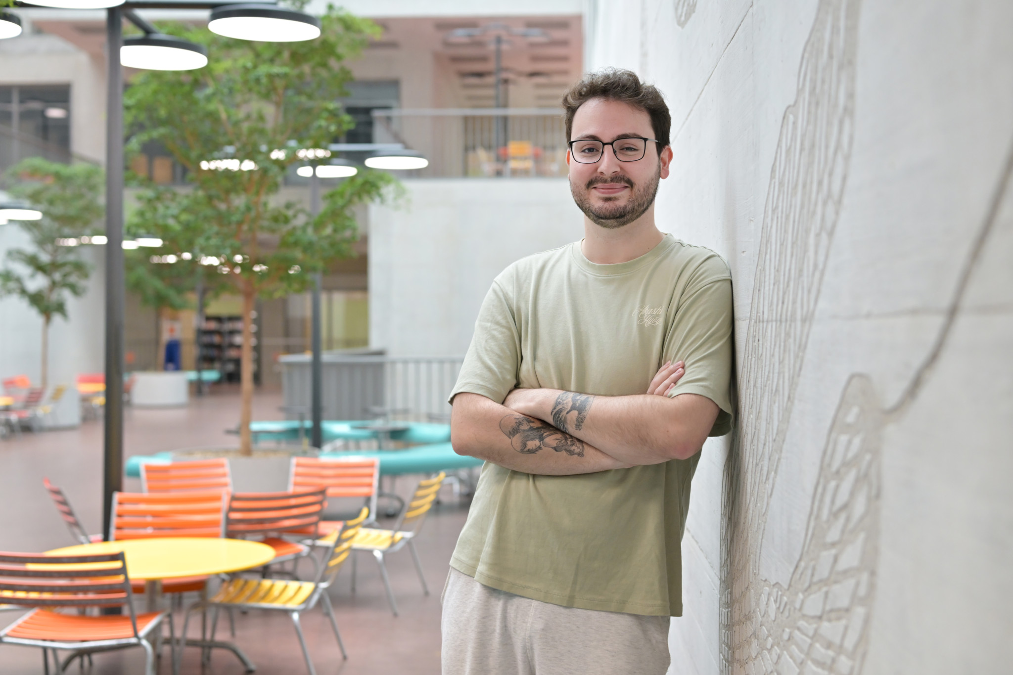 Luca Grieco, der erste männliche Student in der Hebammenausbildung an der ZHAW Winterthur, lehnt lächelnd an einer Wand im Campus-Innenhof.