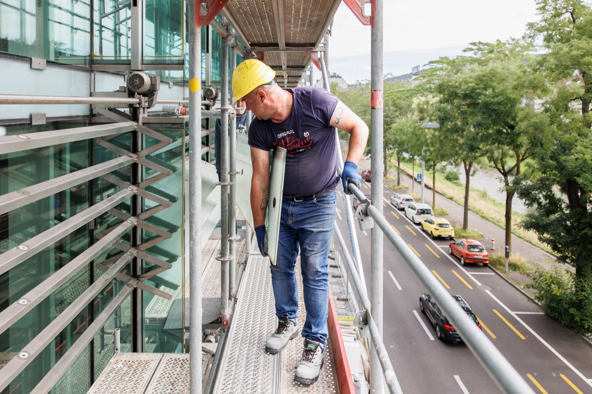 Nicht gerade handlich: Arbeiter müssen die drei Meter langen, 50 Kilo schweren Glasteile um die Gerüststangen zirkeln.