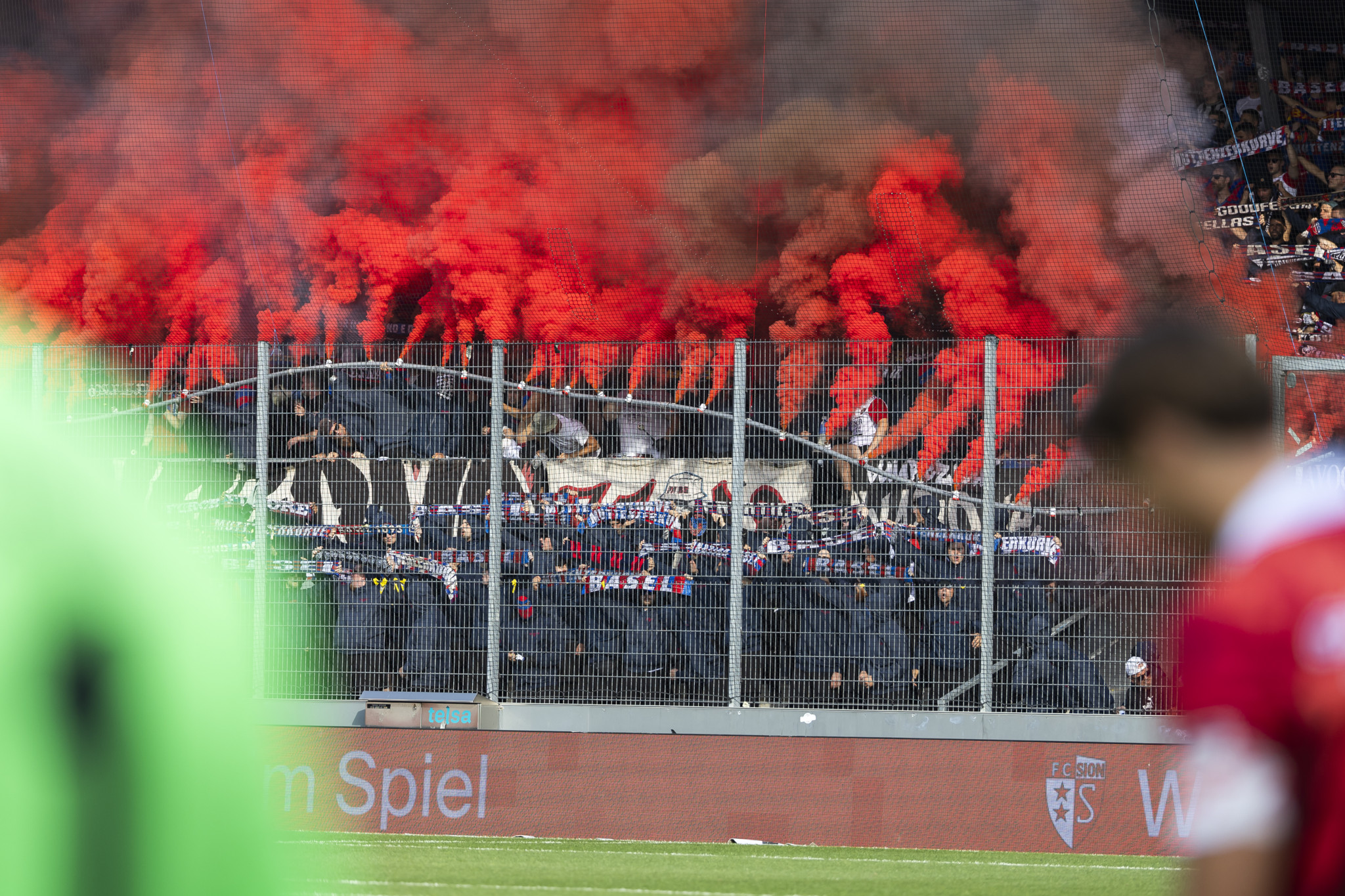 Fans des FC Basel mit roten Fackeln während des Super League Fussballspiels zwischen dem FC Sion und dem FC Basel am Samstag, 31. August 2024 im Tourbillon-Stadion in Sion.