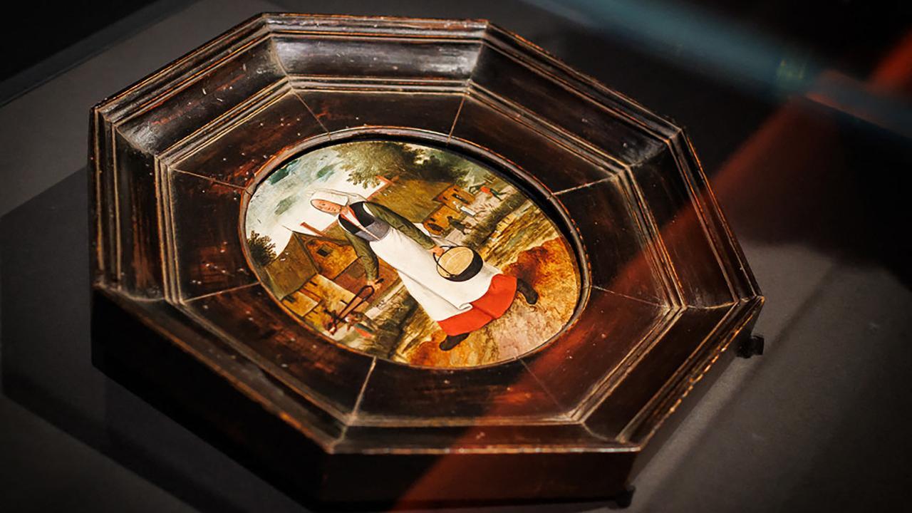 Tableau octogonal représentant une femme en costume traditionnel avec une cruche, devant des maisons dans un cadre champêtre.