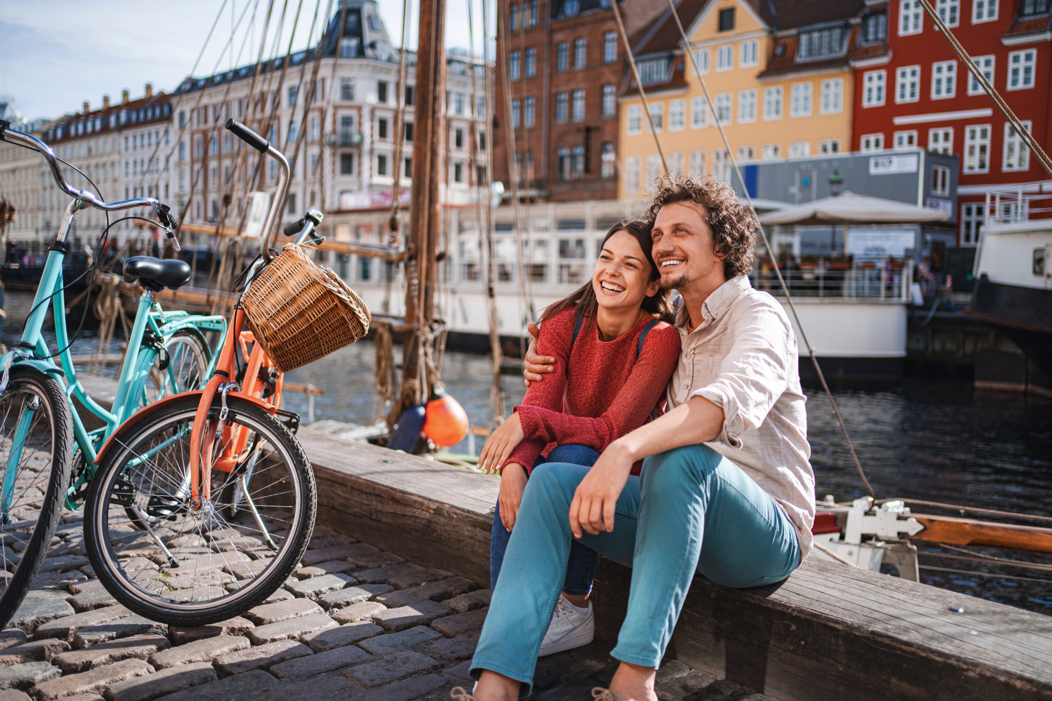 Glückliches Paar in Nyhavn, Kopenhagen, vor bunten Häusern und Fahrrädern, das einen romantischen Moment geniesst.