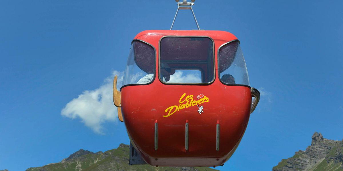 La télécabine rouge d'Isenau aux Diablerets avec un ciel bleu et des montagnes en arrière-plan.