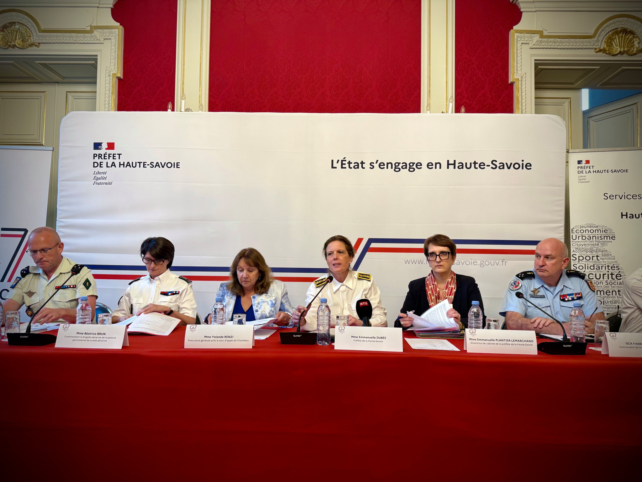 Conférence de presse officielle en Haute-Savoie, six représentants de l’État assis à une table devant la bannière ’L’État s’engage en Haute-Savoie’. Conférence de presse officielle en Haute-Savoie, six représentants de l’État assis à une table devant la bannière ’L’État s’engage en Haute-Savoie’.