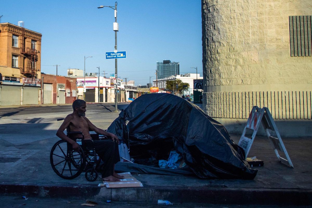 Un homme en fauteuil roulant regarde à côté d'un camp de sans-abri à Los Angeles, Californie, le 26 juillet 2024.
