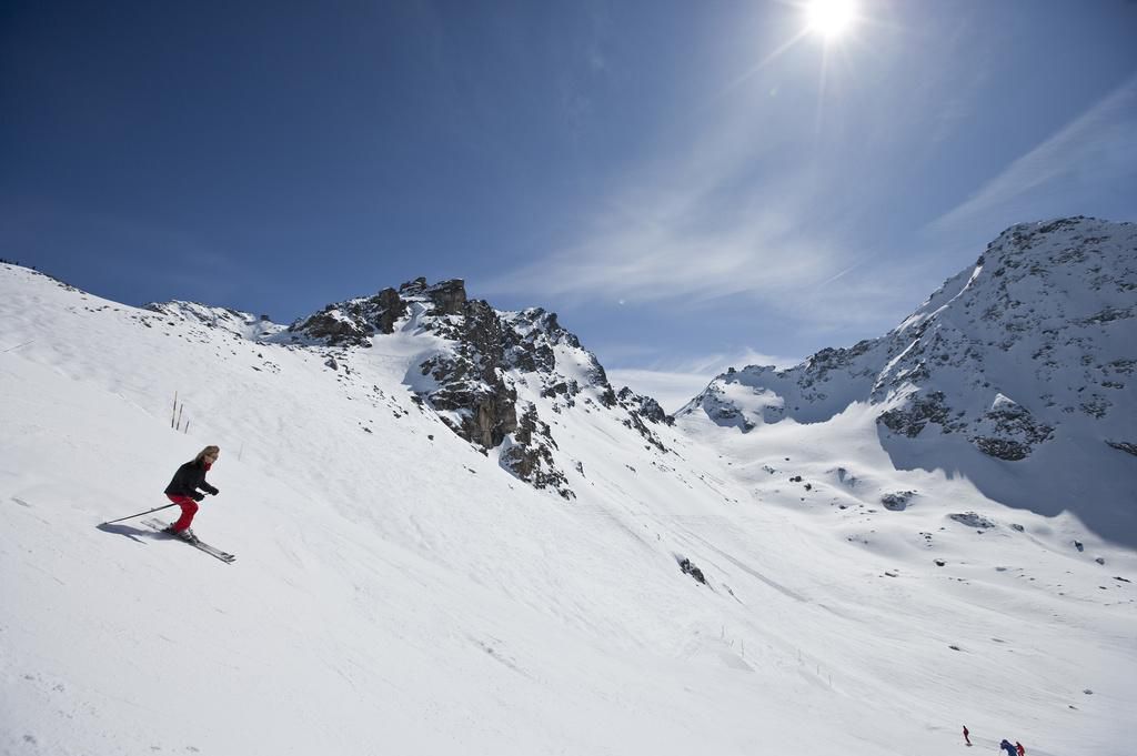 Des skieurs descendent la pente entre le sommet ’Col des Gentianes’ et ’La Chaux’ dans la station de ski de Verbier, Valais, Suisse, sous un ciel ensoleillé.