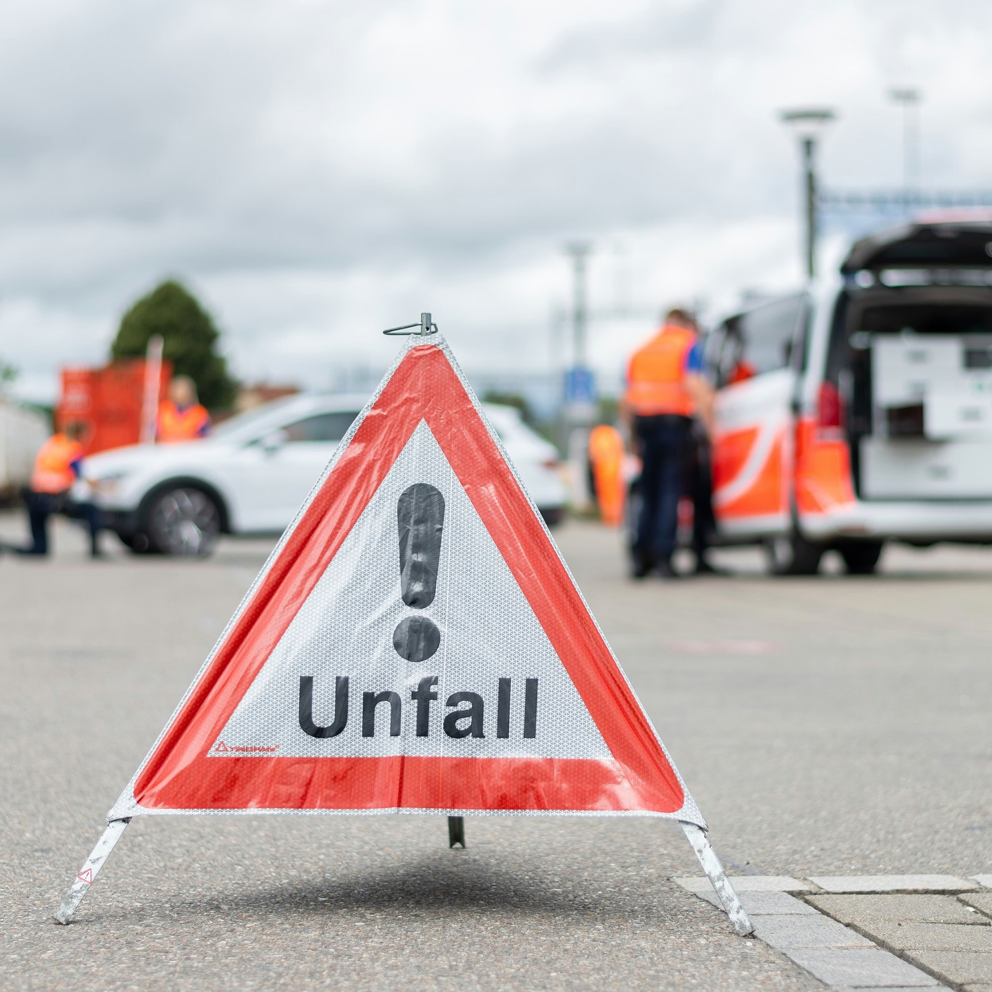 Verkehrsunfall-Warnschild mit der Aufschrift ’Unfall’ auf einer Strasse, Polizisten im Hintergrund.