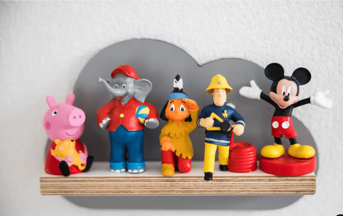 Figurines colorées de personnages célèbres alignées sur une étagère en forme de nuage.