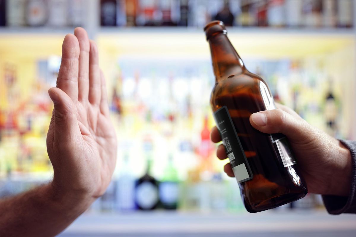 Main rejetant une bière, symbolisant le refus de l’alcool et l’addiction.