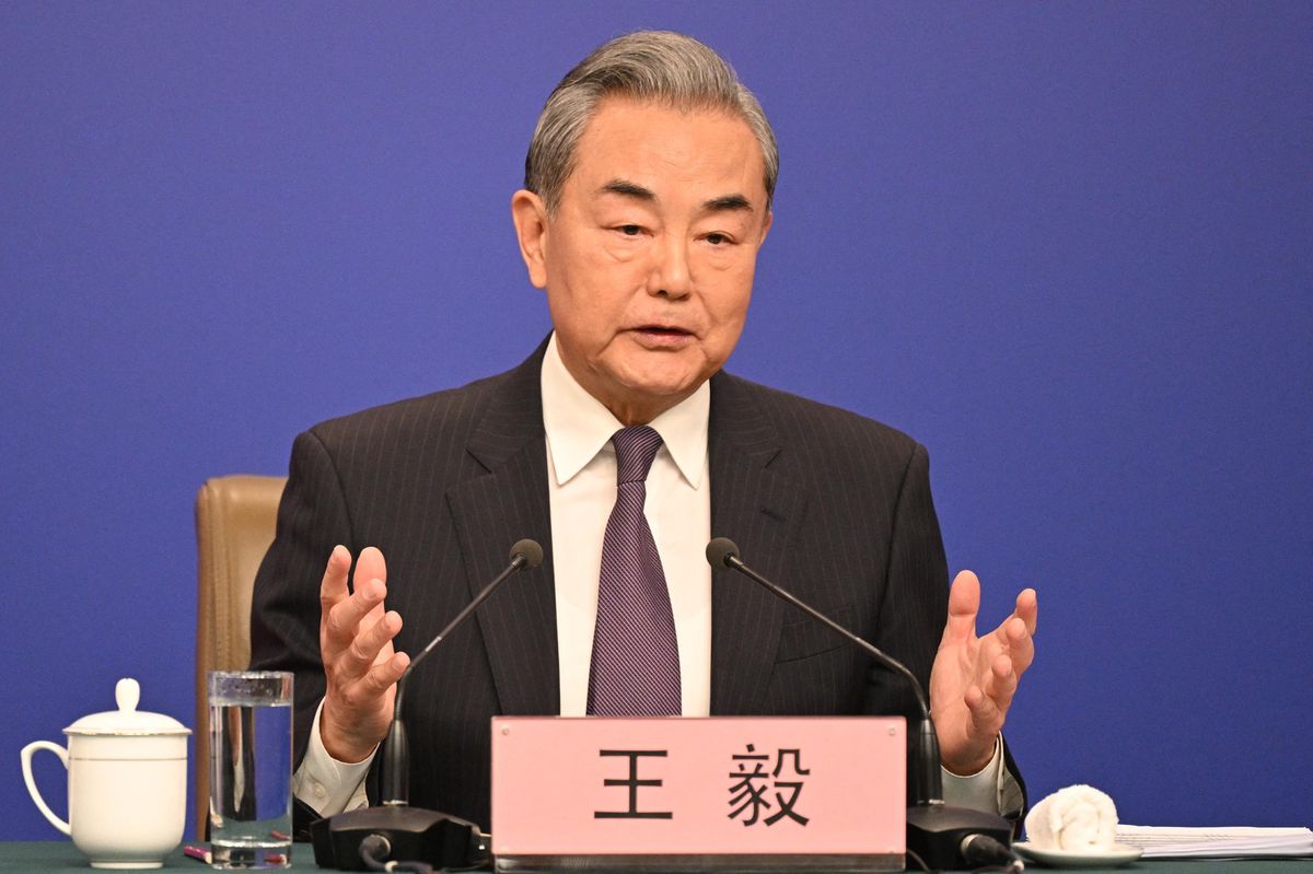 Le ministre chinois des Affaires étrangères Wang Yi s’exprime lors d’une conférence de presse au Congrès national du peuple à Pékin, le 7 mars 2025, avec une tasse et un verre d’eau sur la table devant lui sur fond bleu.