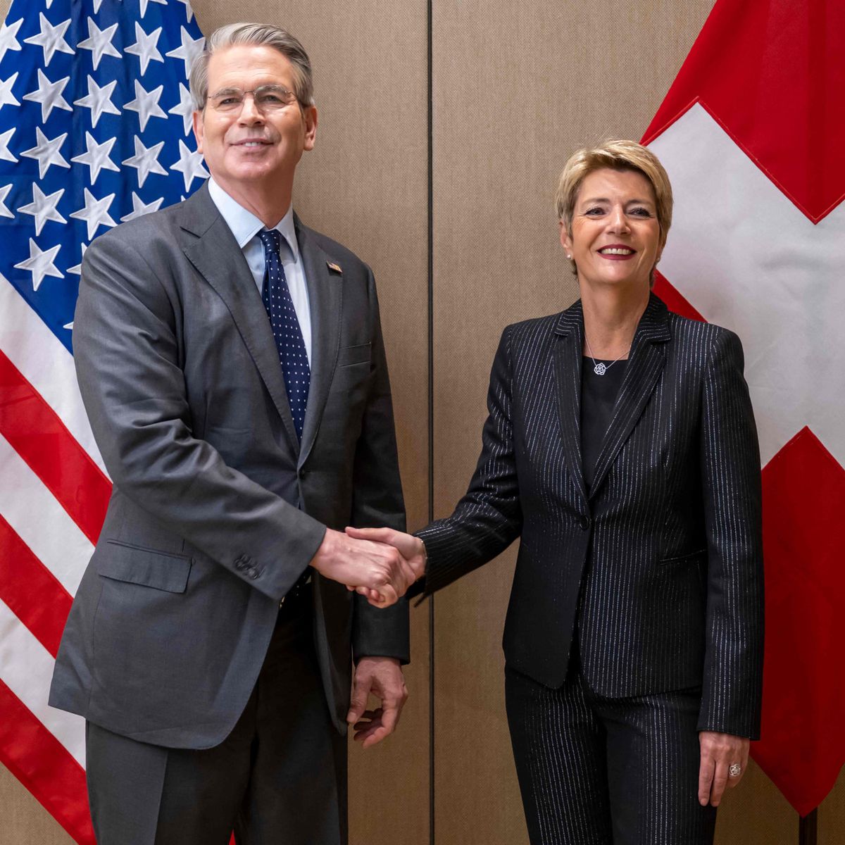 US-Finanzminister Scott Bessent schüttelt der Schweizer Präsidentin Karin Keller-Sutter vor einer bilateralen Sitzung in Genf am 9. Mai 2025 die Hand. Im Hintergrund sind die Flaggen der USA und der Schweiz zu sehen.
