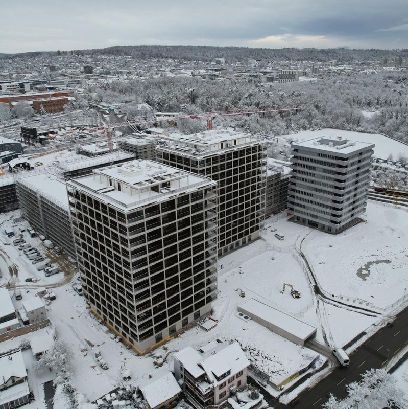 Verschneite Stadtansicht mit hohen Gebäuden, Strassen und umliegendem Wald in winterlicher Landschaft. Verschneite Stadtansicht mit hohen Gebäuden, Strassen und umliegendem Wald in winterlicher Landschaft.