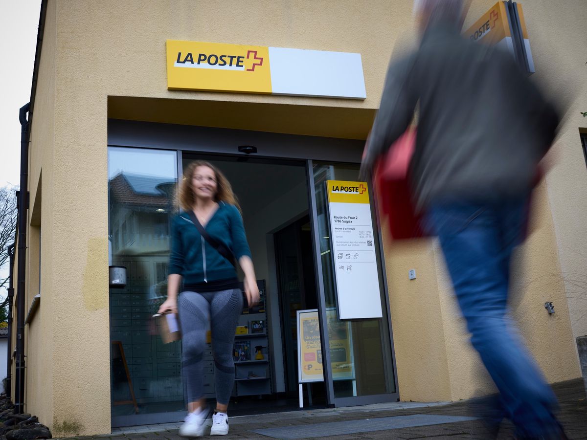 Personnes entrant et sortant d'un bureau de poste à Sugiez, illustrant la fermeture prochaine des locaux. Photo prise par Yvain Genevay.