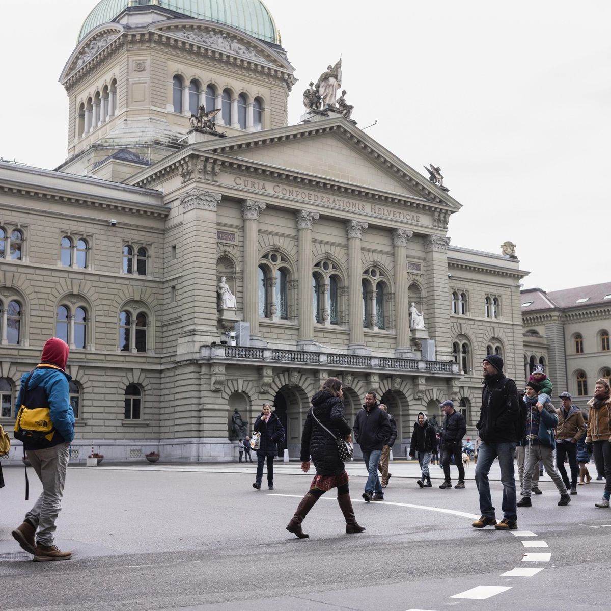 Des gens non masqués marchent ensemble sur la Bundesplatz à Berne, devant un bâtiment historique, le 13 décembre 2020.