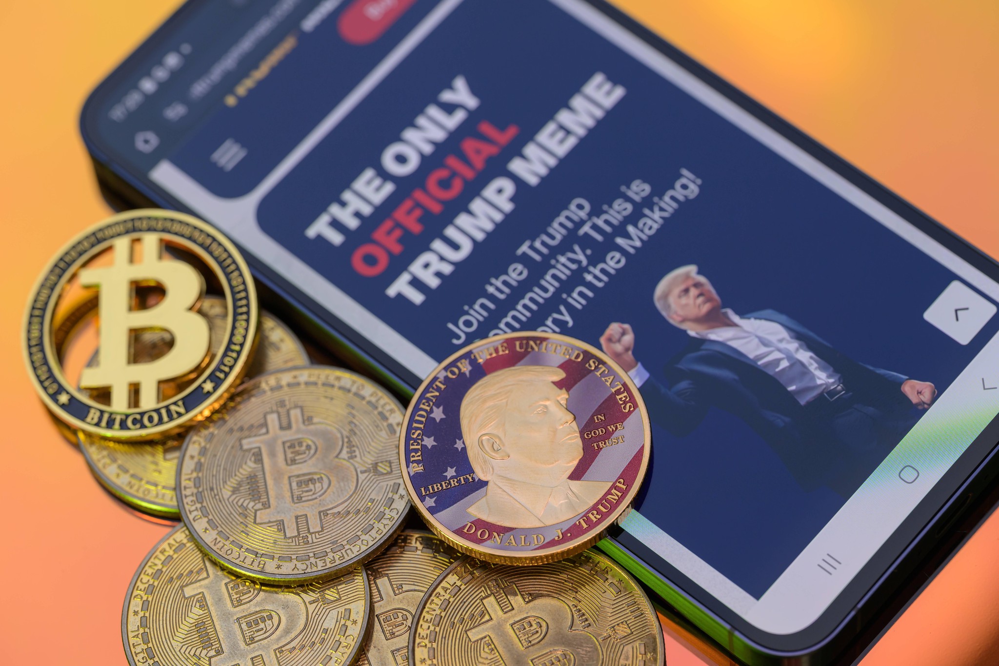 Abbildung der Krypto-Münze $Trump Meme Coin neben Bitcoin-Münzen und einer Handy-Bildschirmanzeige mit der Aufschrift ’The Only Official Trump Meme’. Aufgenommen in Brüssel, Belgien, am 2. März 2025.
