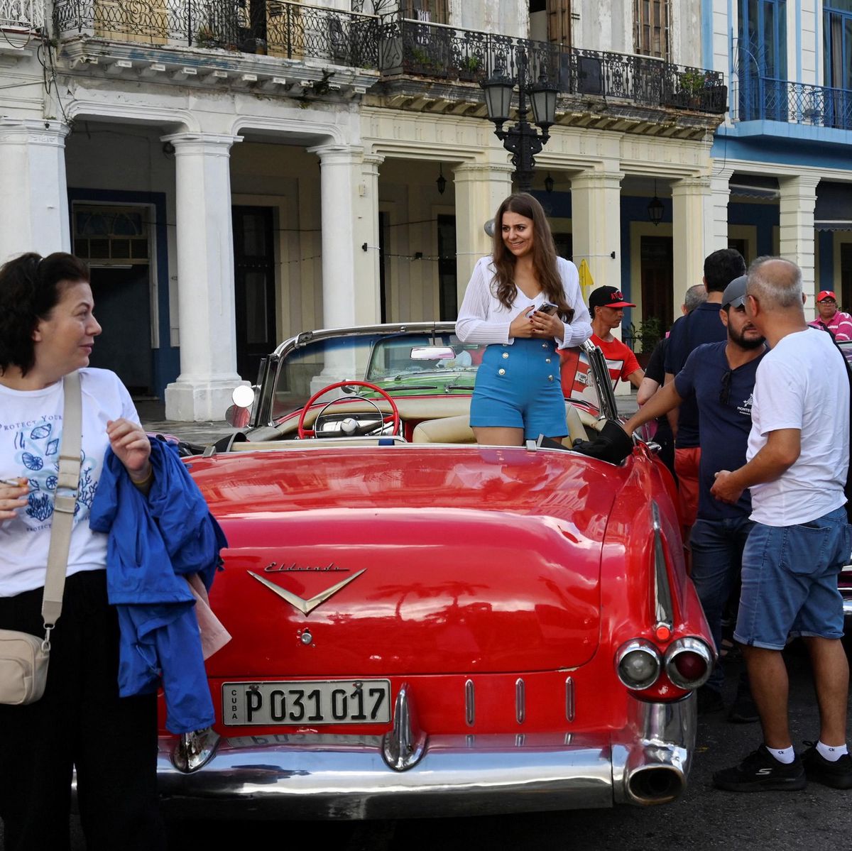 Des touristes attendent pour monter dans une voiture américaine classique dans une rue de La Havane le 21 octobre 2024, reflétant le tourisme en déclin à Cuba malgré la crise économique.