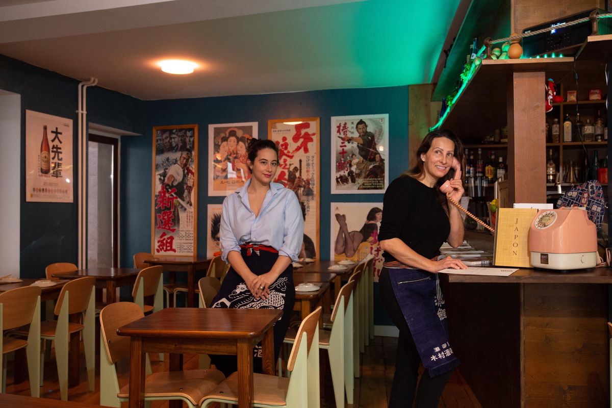 Intérieur du restaurant Amagaki à Genève avec deux femmes travaillant à l’accueil, entourées de décorations murales.