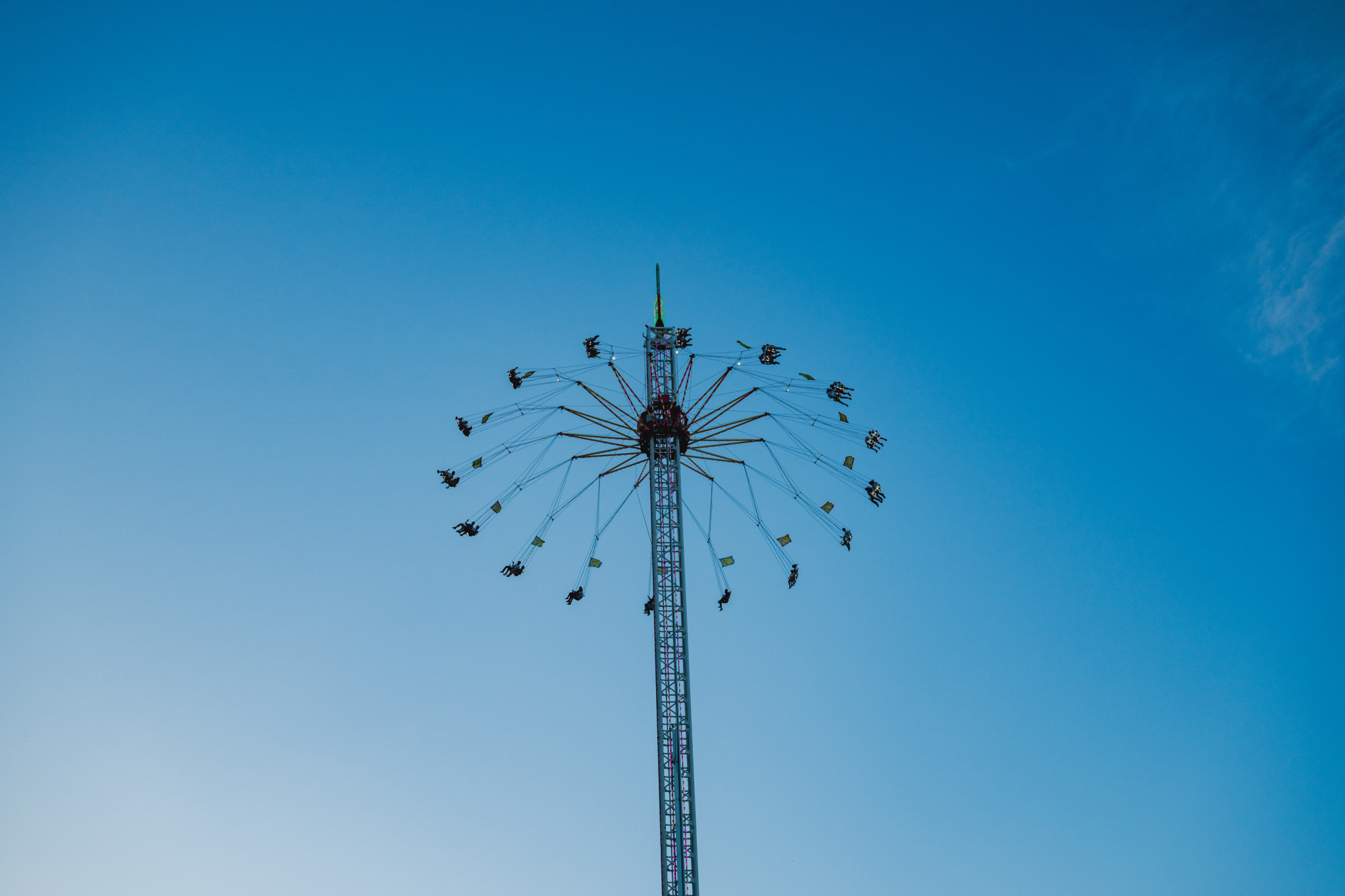 Ein hoher Kettenkarussell-Turm beim Knabenschiessen 2024 vor klarem blauem Himmel.