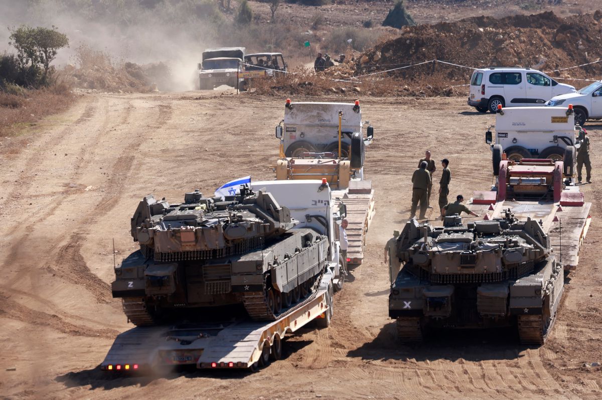 Deux chars israéliens transportés vers une position dans la région de Galilée supérieure, au nord d'Israël, près de la frontière avec le Liban, le 29 septembre 2024. Des véhicules militaires et des soldats sont également visibles.