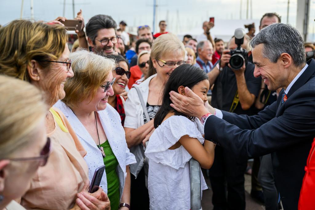 Le President de la Confederation Ignazio Cassis, droite, parle avec la Presidente du Conseil d'Etat vaudois Christelle Luisier, centre, dans le train entre Yverdon et Lausanne pour la celebration de la Fete nationale lors d'un Tour de Suisse en train le lundi 1 aout 2022 a Lausanne. (KEYSTONE/Jean-Christophe Bott)