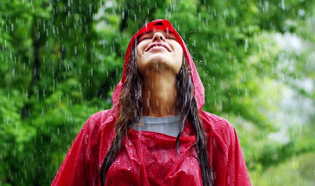 girl smiles, spins and laughs in the rain. the rain falls, the drops fall on his face and the girl is happy with life and nature around. concept of nature and happy life. Adventure, purity.