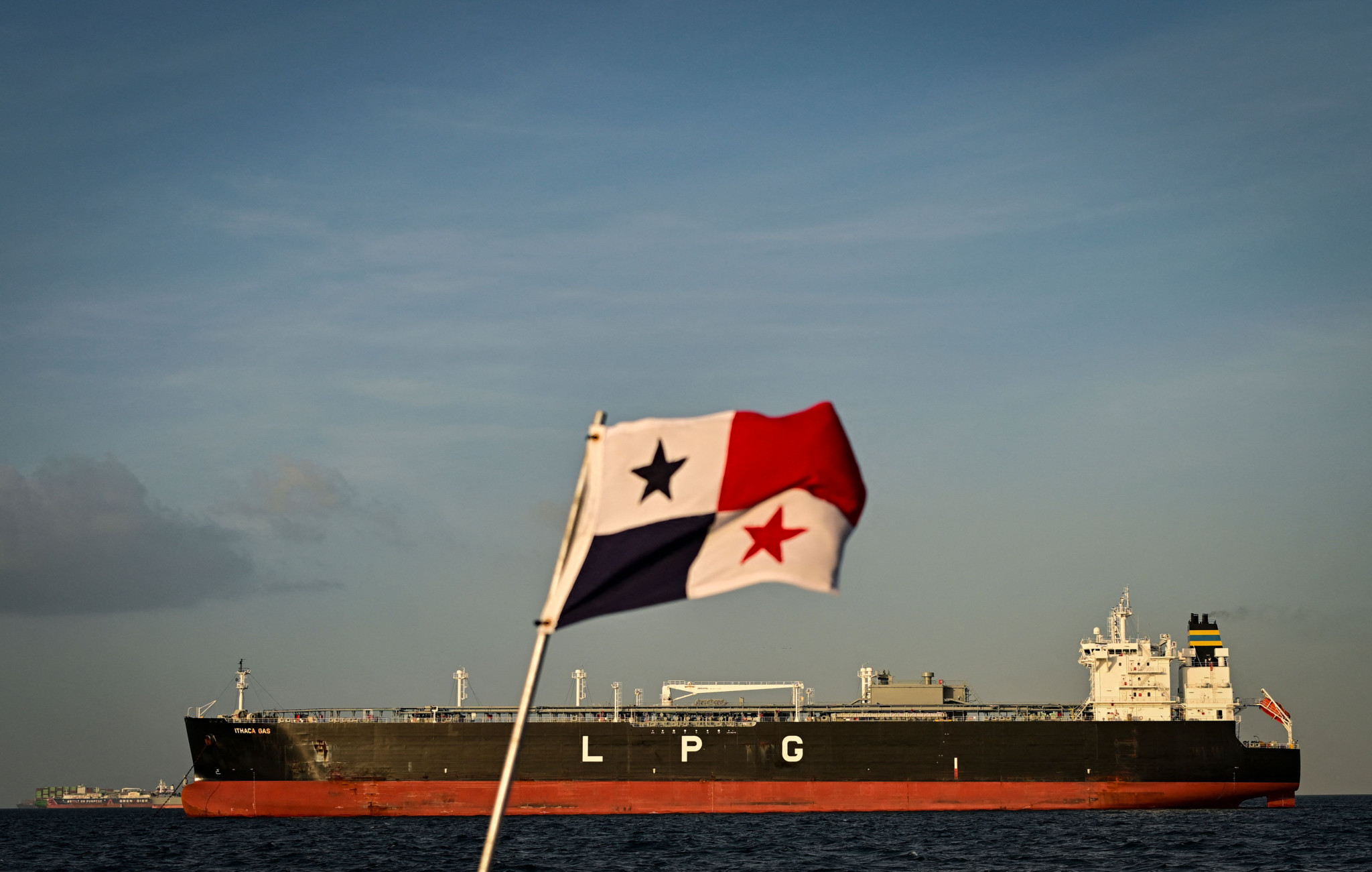Ein LPG-Frachtschiff wartet vor dem Panamakanal in Panama City, im Vordergrund weht eine panamaische Flagge.