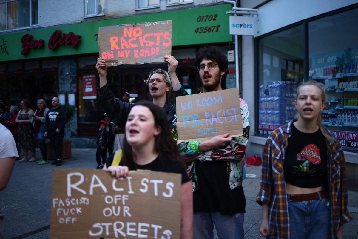 People hold anti-racism placards during a counter demonstration against an anti-immigration protest called by far-right activists, near an Immigration Solicitors' office in Westcliff, near Southend-on-Sea, eastern England on August 7, 2024. Thousands of riot police stood ready Wednesday as Britain remained on alert for disturbances during far-right protests across the country. Nightly riots, during which mosques and migrant targets have been attacked, erupted after three children were murdered in Southport on July 29. (Photo by AFP)