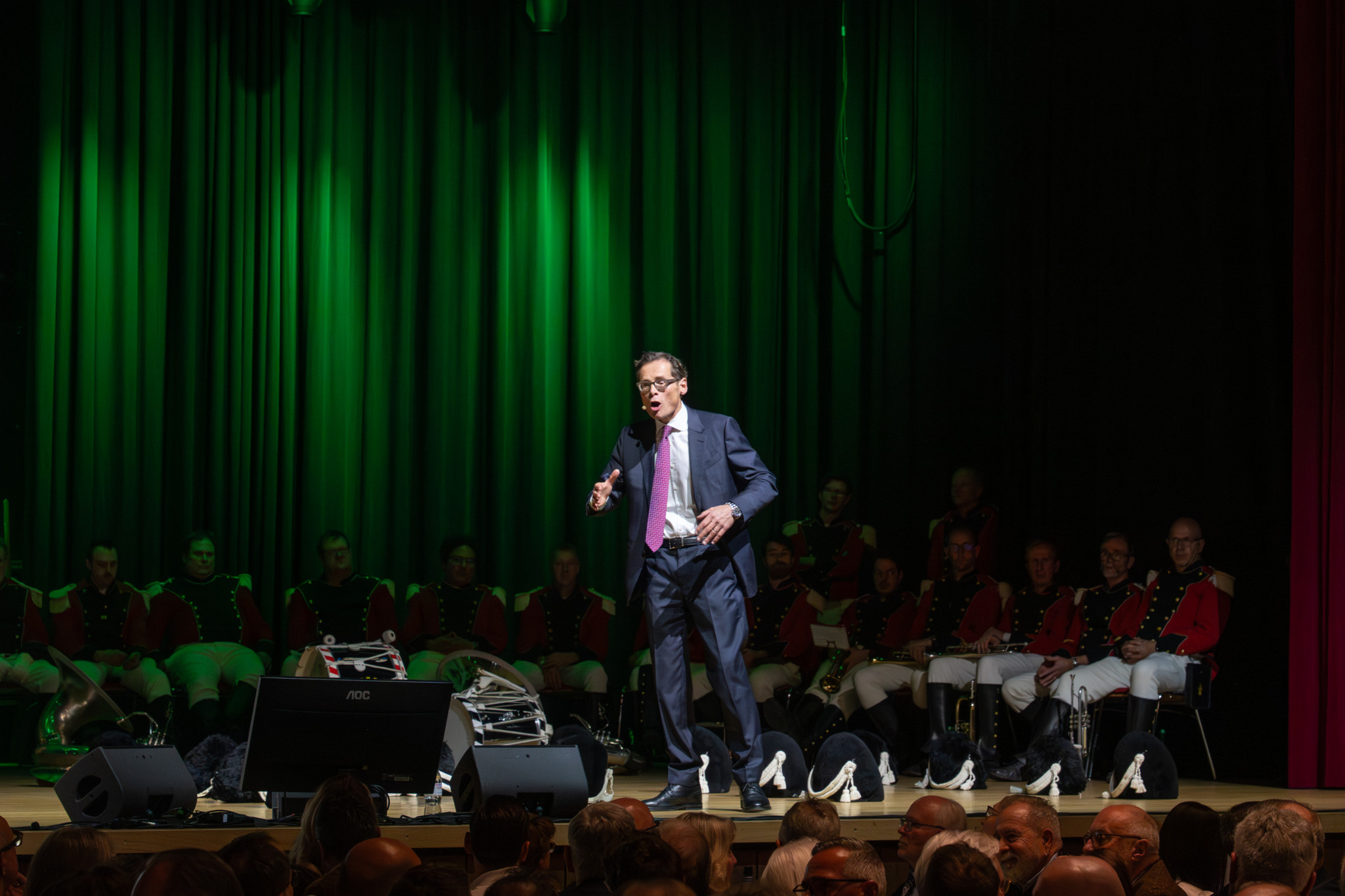 Ein Mann in Anzug spricht in ein Mikrofon auf einer Bühne bei der Albisgüetlitagung 2026, umgeben von uniformierten Personen im Hintergrund.