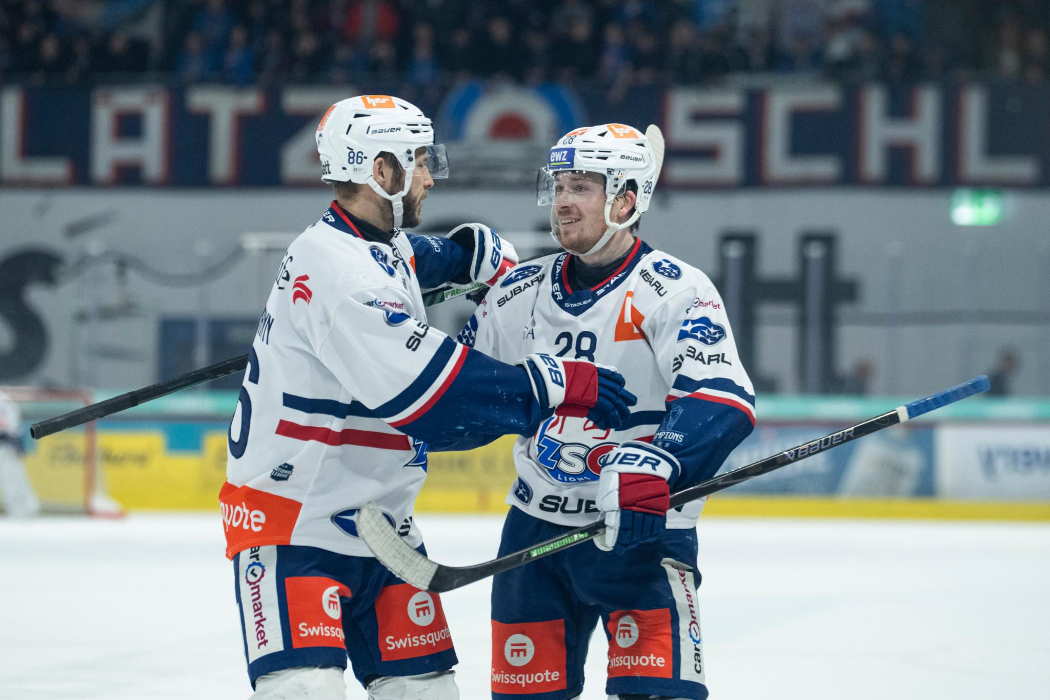 Jesper Froeden und Dario Trutmann von den ZSC Lions jubeln nach einem Tor während eines Eishockeyspiels gegen EHC Kloten.