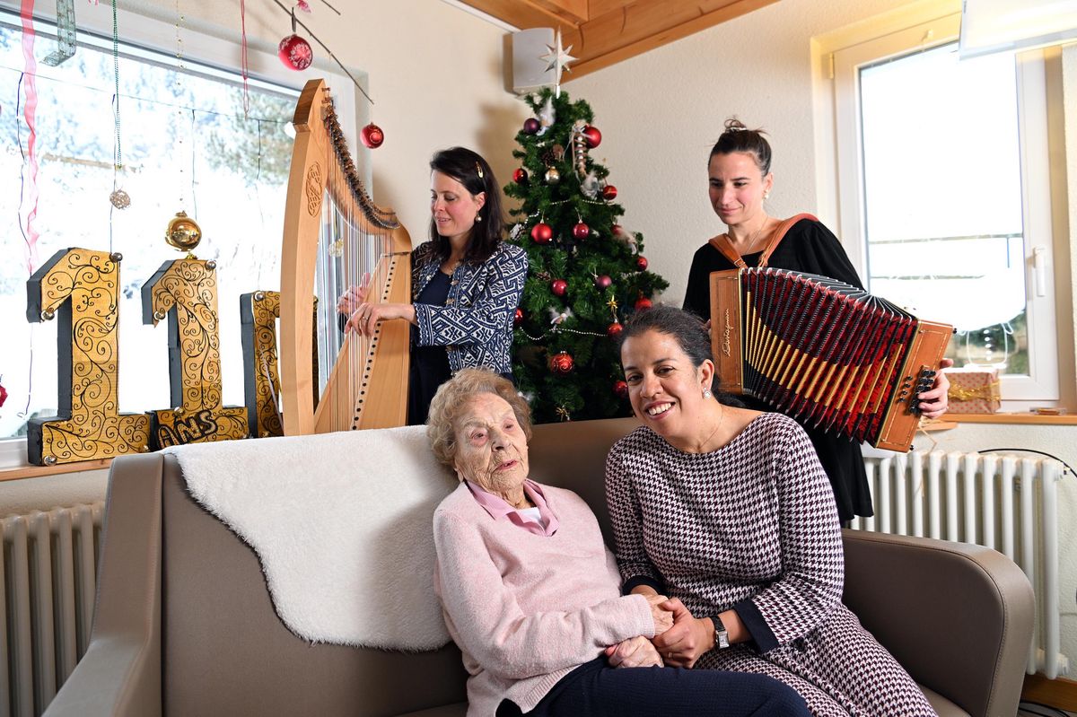 Le Chenit,  le 4  janvier 2025.  Francine Grandjean Baud, doyenne vaudoise, fête ses 110 ans au foyer Agapê à Orient dans la Vallée de Joux. Elle est ici en compagnie de Landy Niaritsiry la directrice du home et les musiciennes du groupe les Etourdyons, Morgane à la harpe et Juliana à l'accordéon. 24HEURES/Chantal Dervey